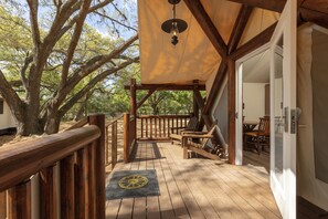 A wooden deck with a pergola, outdoor seating, and a door leading to an interior space.