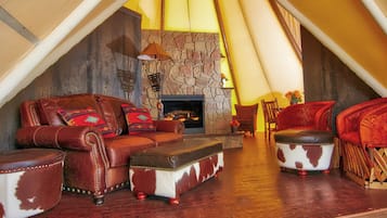 Una sala acogedora con sofás de cuero, una chimenea de piedra y piso de madera.