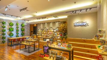 A modern retail store with wooden flooring, a central display table, and shelves stocked with various products.