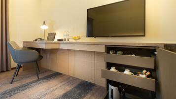 Ein modernes Hotelzimmer mit Schreibtisch, Stuhl, Flachbildfernseher und integrierten Stauraum.