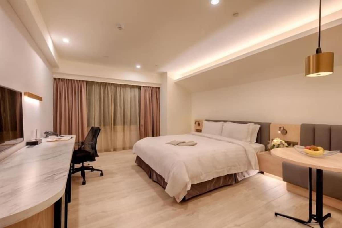 Una habitación de hotel moderna con una cama, un escritorio y un pequeño comedor.