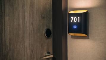 Une porte en bois dotée d’un trou de serrure et d’un luminaire moderne affichant le numéro 701.