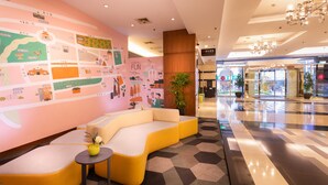 Een moderne lobby met een kleurrijke muurschildering, een gele bank en een klein tafeltje met een vaas.