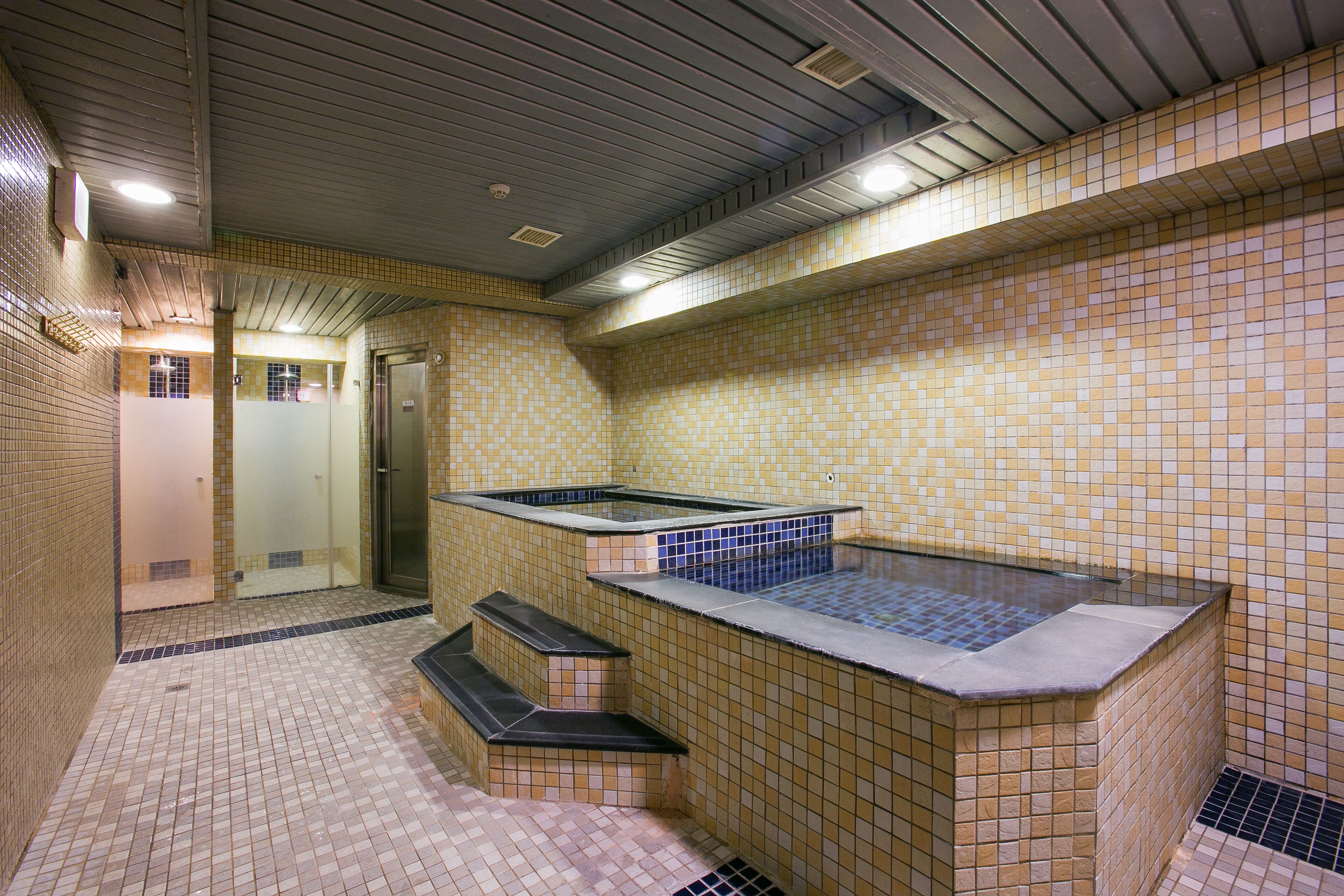 A spa area with a hot tub, tiled walls, and a shower area.