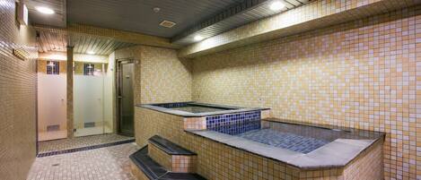 A spa area with a hot tub, tiled walls, and a shower area.
