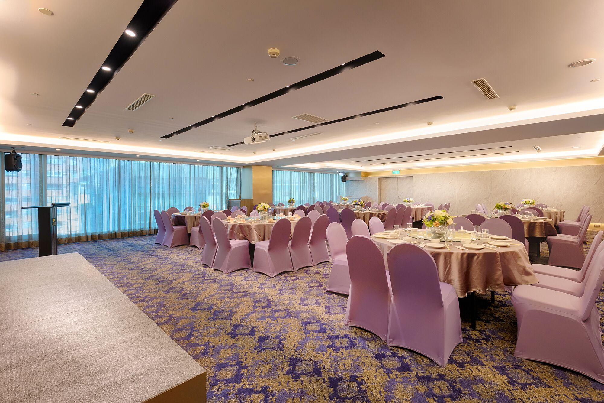 A large conference room with round tables, purple chairs, and a carpeted floor.