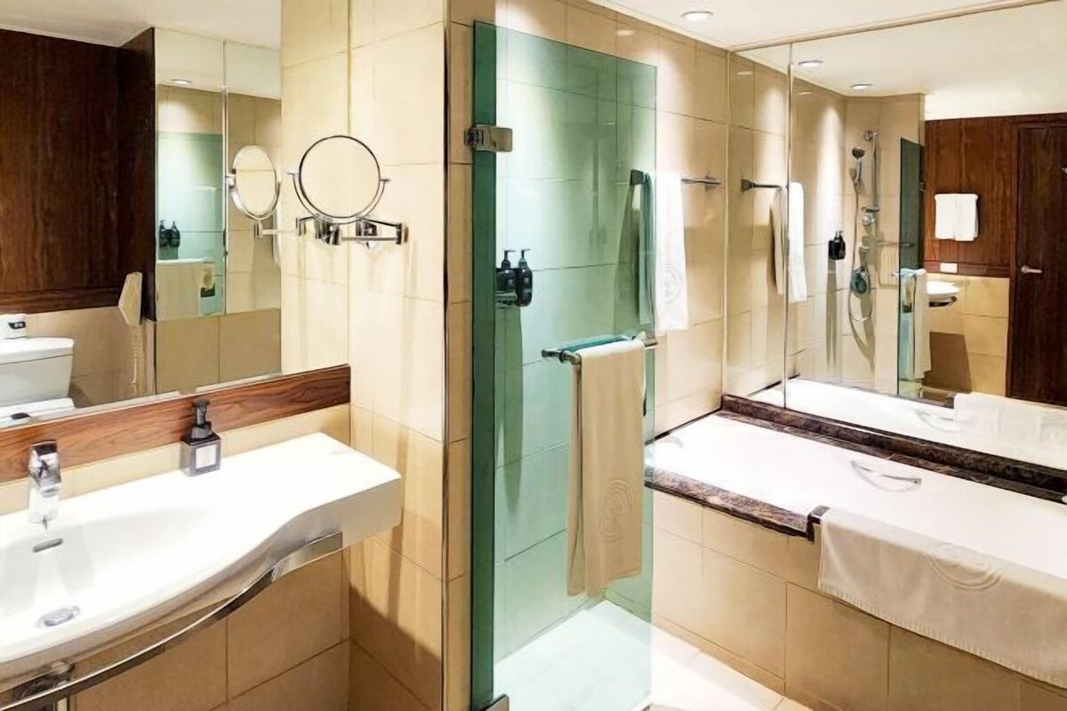 Un baño moderno con dos lavamanos, una cabina de ducha de vidrio y un espejo grande.