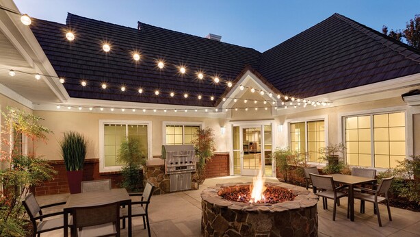 A patio with a stone fire pit, outdoor seating, a grill, and string lights. - Residence Inn by Marriott Sacramento Folsom (Folsom)