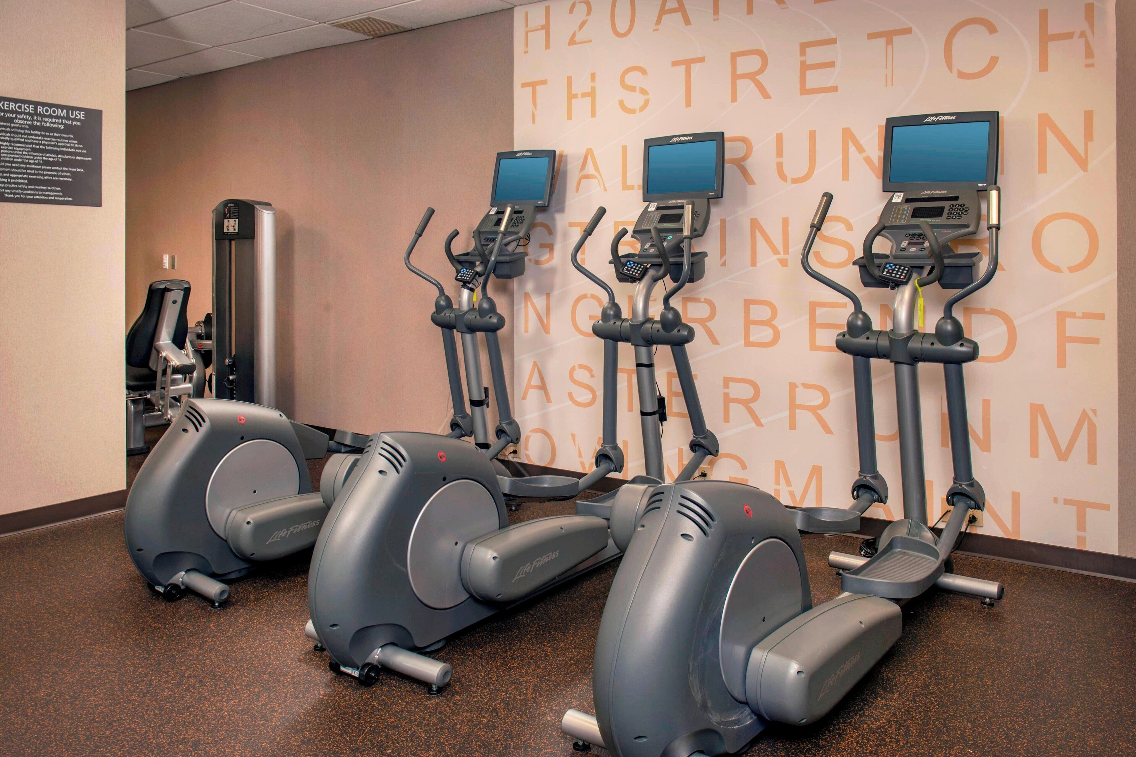 Un gimnasio con cintas de correr y una pared con mensajes motivacionales.