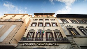 Exterior del Hotel Palazzo Strozzi, cielo despejado y varias banderas.