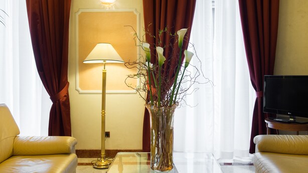Una habitación con un sofá, una mesa con un florero, una lámpara y un televisor.