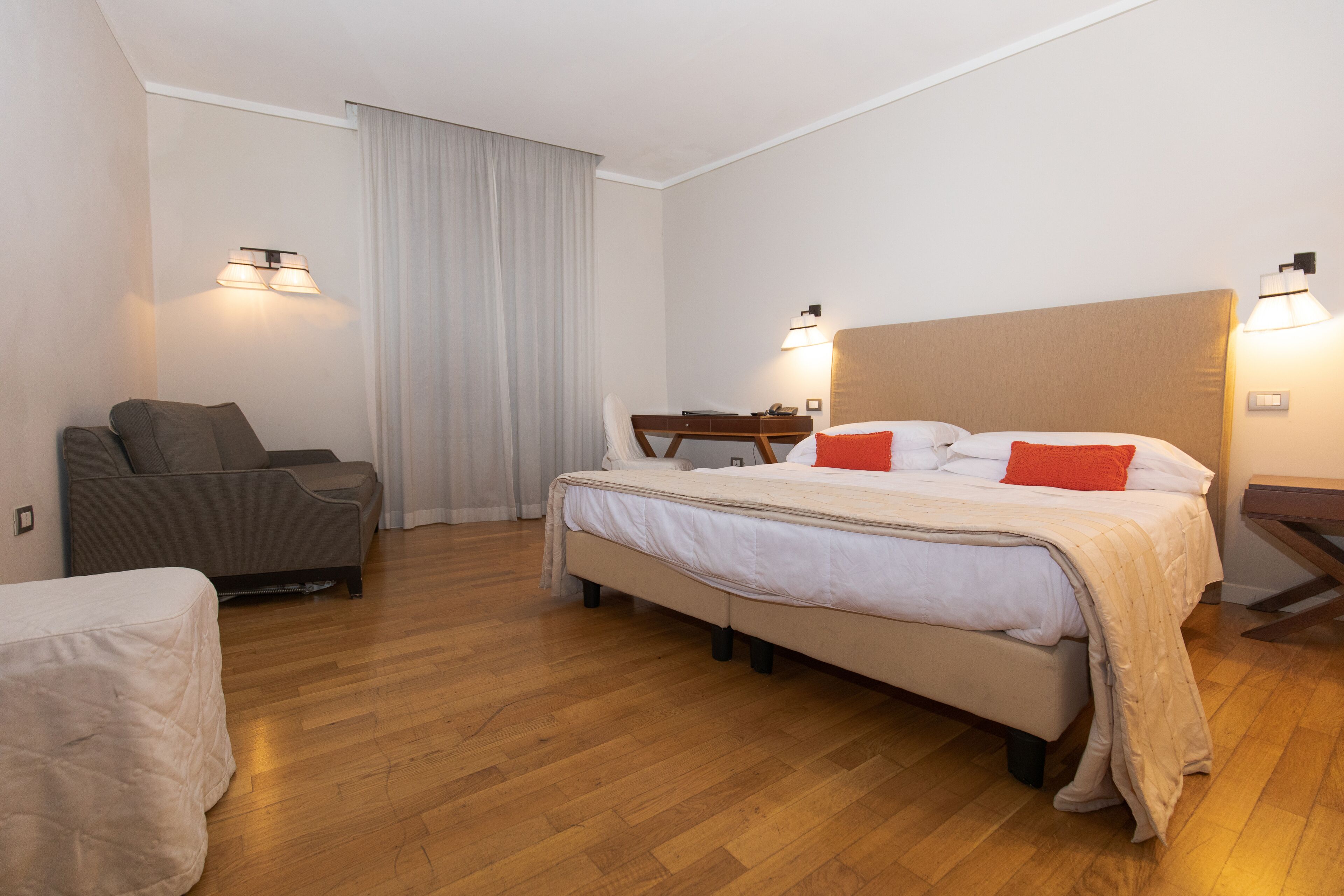 A hotel room with a bed, a sofa, a desk, and a chair.