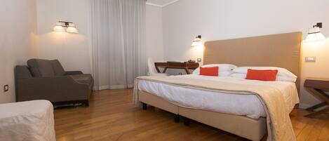 A hotel room with a bed, a sofa, a desk, and a chair.