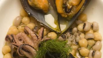 A plate of mussels, octopus, and beans with a sprig of dill.