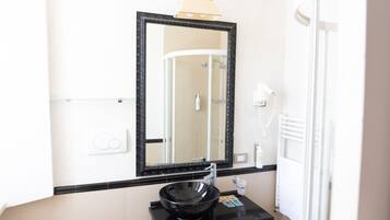 A bathroom with a black sink, a mirror, and a towel rack.