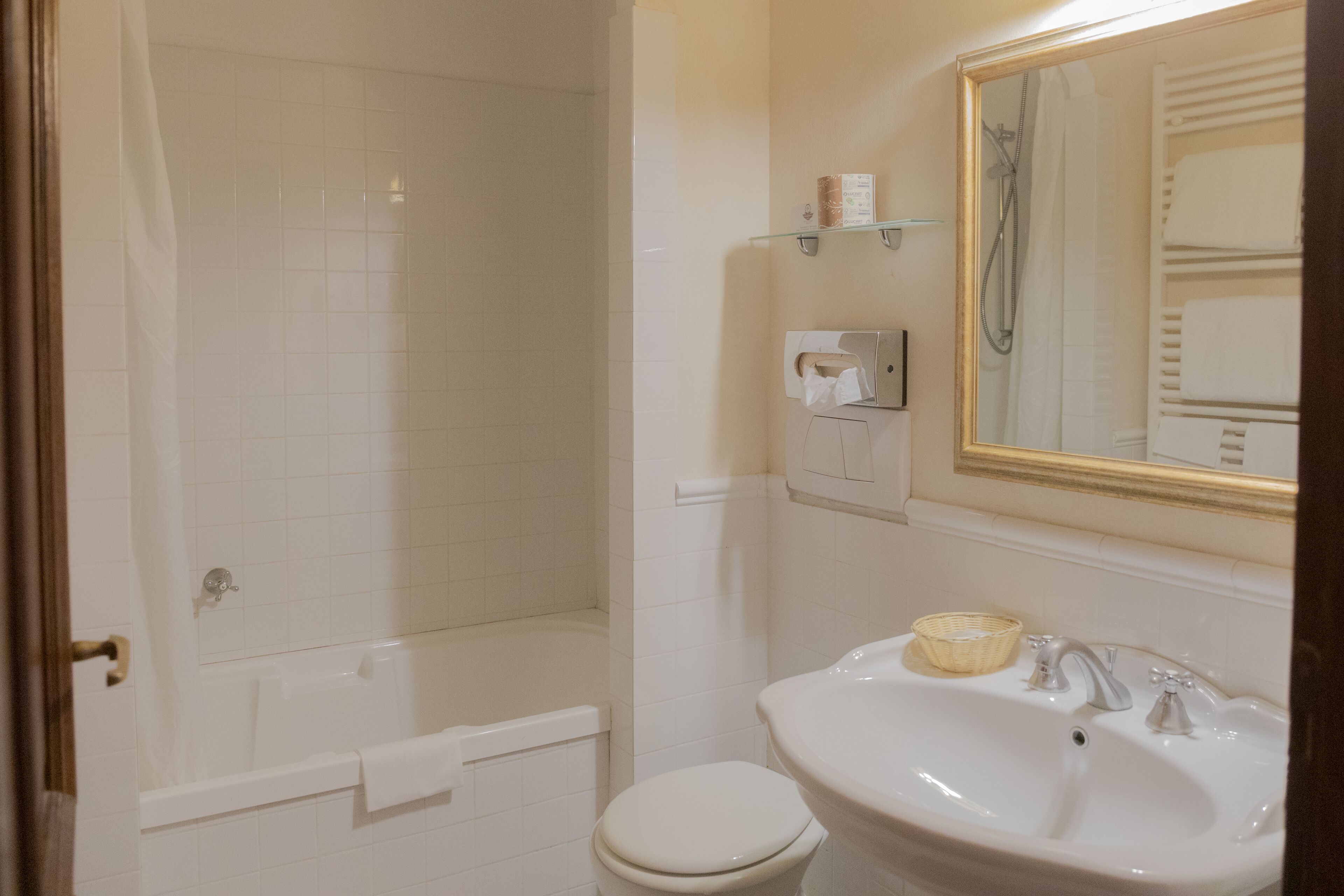 A bathroom with a bathtub, toilet, sink, and a mirror.