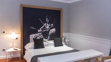 Ein Schlafzimmer mit einem Bett, einem Nachttisch, einer Lampe und einem großen gerahmten Bild an der Wand.