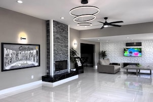 Una sala de estar moderna con chimenea, ventilador de techo y televisor de pantalla plana montado en la pared.