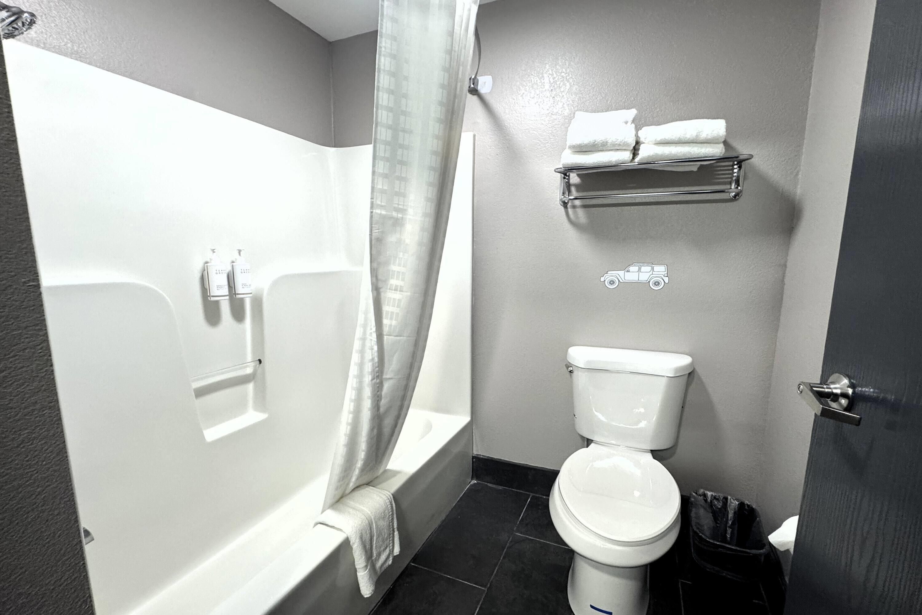 A bathroom with a bathtub, toilet, and a towel rack.