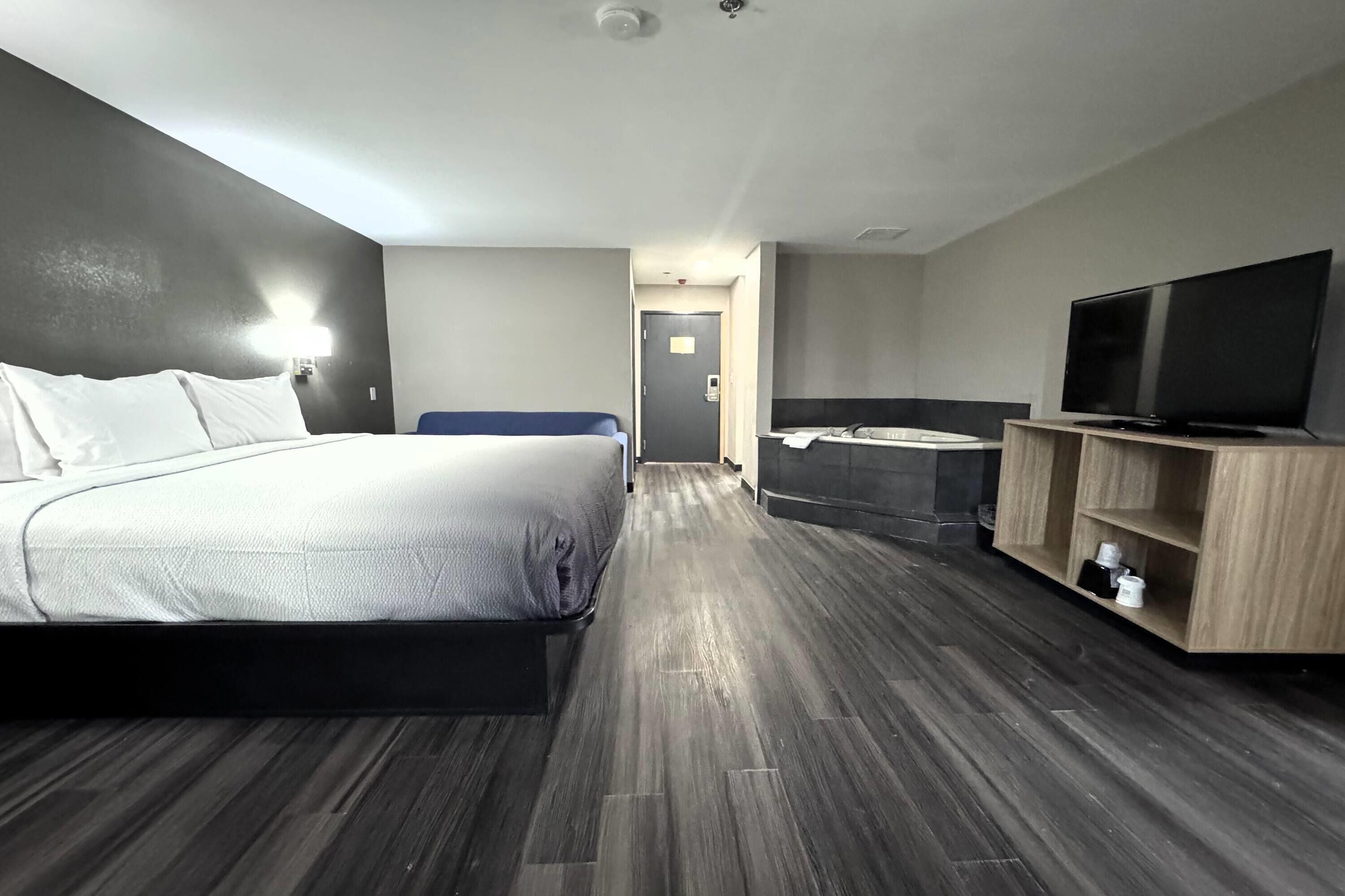 Ein Hotelzimmer mit Bett, Fernseher, Badezimmer und Flur.