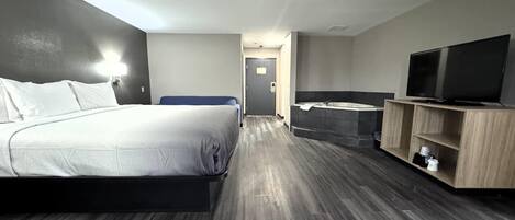 Ein Hotelzimmer mit Bett, Fernseher, Badezimmer und Flur.