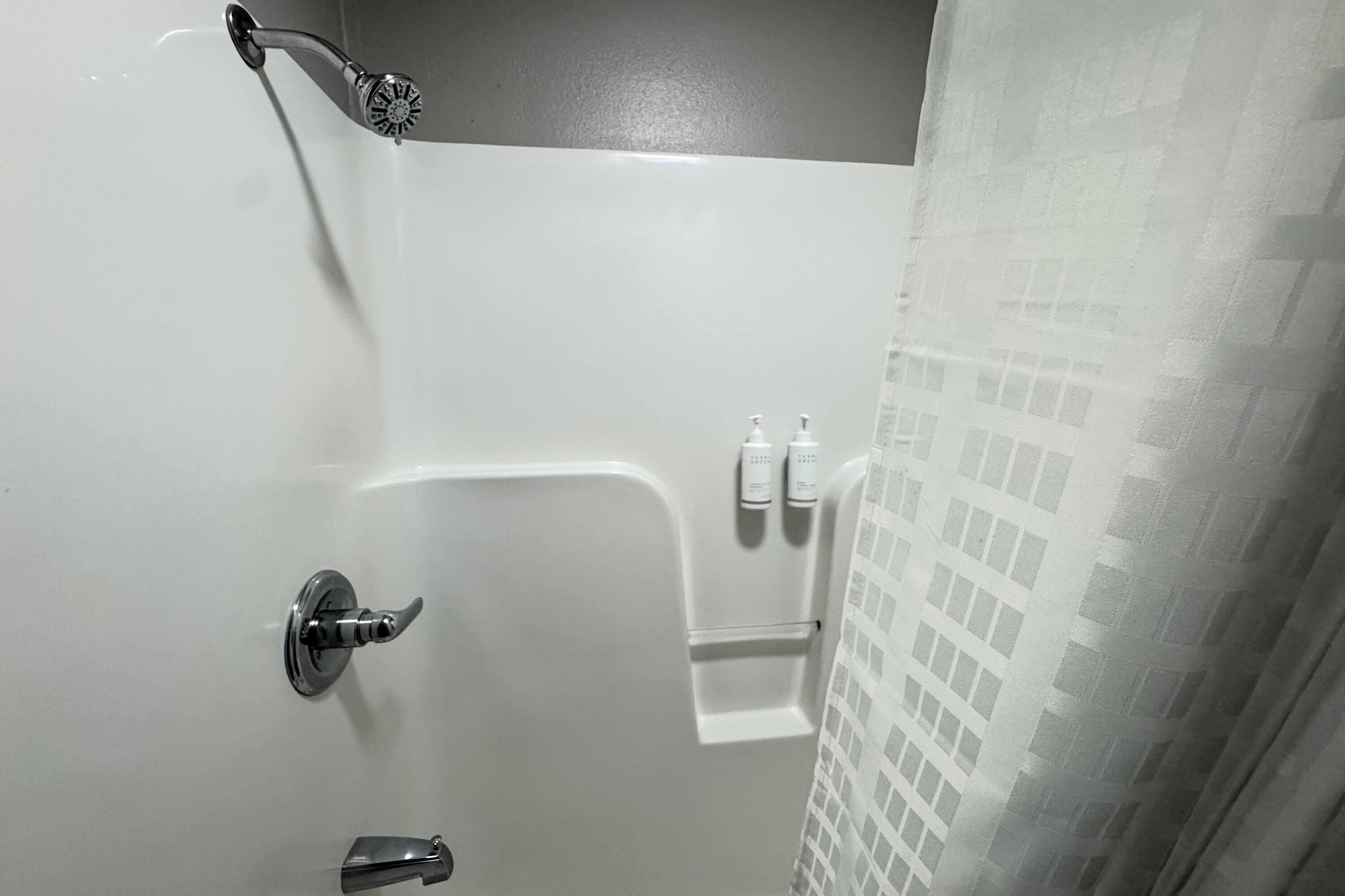 A bathroom with a shower, a toilet, and a towel rack.