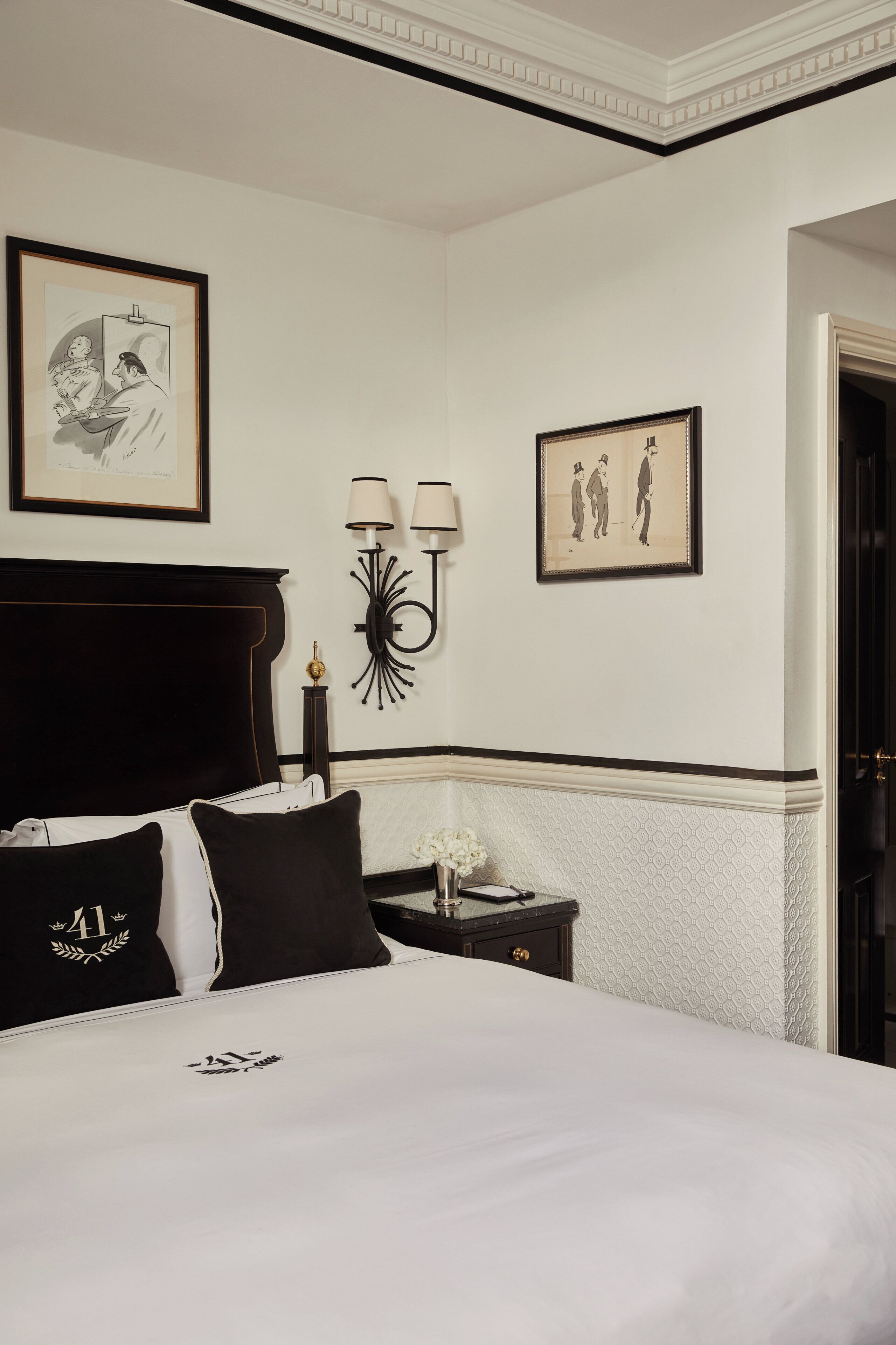 A neatly made bed with black and white bedding, a dark headboard, and a small bedside table with a lamp.