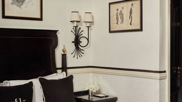A neatly made bed with black and white bedding, a dark headboard, and a small bedside table with a lamp.