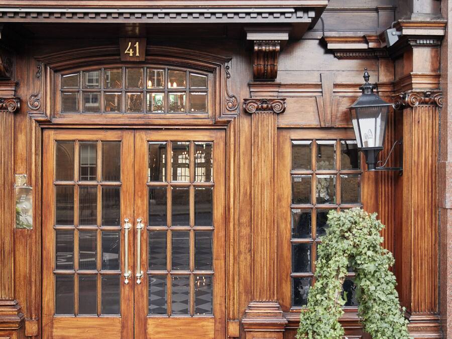 A wooden double door with the number 41, a welcome mat, and a black planter with greenery.
