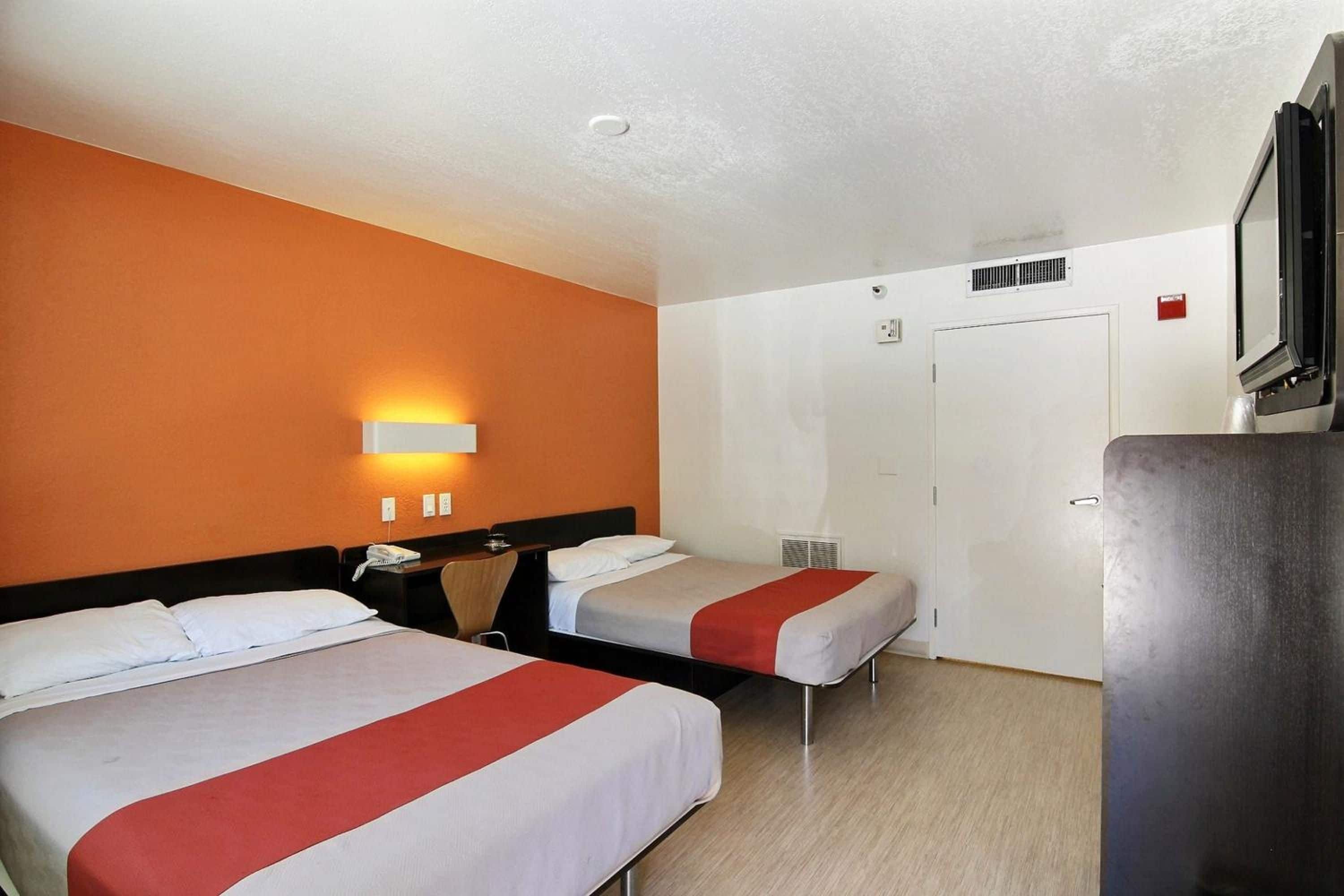 A hotel room with two beds, a desk, a chair, a TV, and a wardrobe.