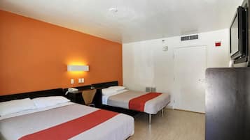 A hotel room with two beds, a desk, a chair, a TV, and a wardrobe.