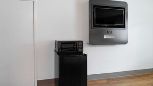 A compact microwave on a small black stand, a white door, and a wall-mounted microwave.