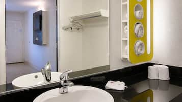 Un baño con un lavamanos blanco, un espejo y un toallero amarillo.
