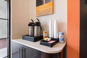 A coffee station with a coffee maker, creamers, sugar, and disposable cups. - Vagabond Inn Santa Barbara - Carpinteria South (Carpinteria)