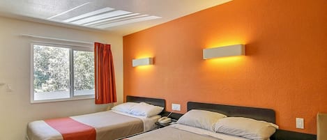 Habitación de hotel con dos camas, una ventana con cortinas, una lámpara de techo y una lámpara de pared.