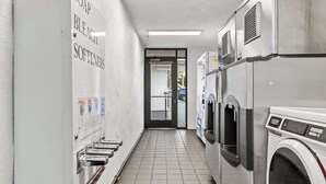 A laundry facility with multiple washing machines and a wall-mounted soap and bleach dispenser.