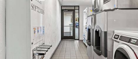 A laundry facility with multiple washing machines and a wall-mounted soap and bleach dispenser.