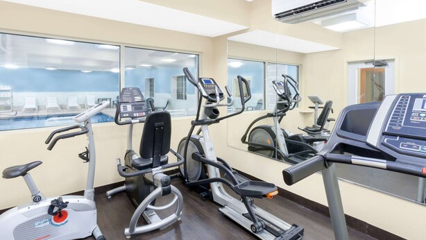 A gym with cardio machines, a treadmill, and a mirrored wall. - Baymont by Wyndham Fort Wayne (Fort Wayne)