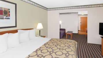 Habitación de hotel con cama, escritorio, silla, televisor y un cuadro en la pared.