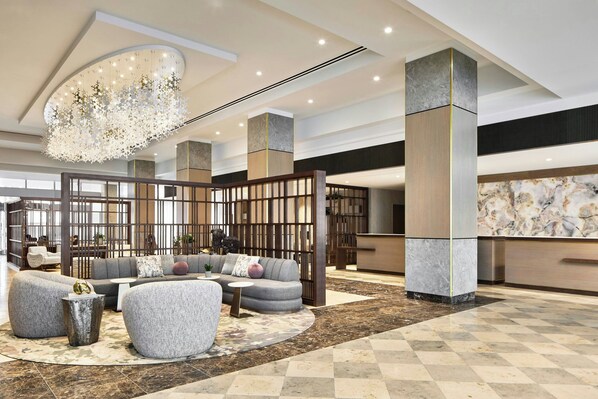 A spacious lobby with a modern sofa set, a round coffee table, and a decorative chandelier. - The Westin Charlotte (Charlotte)