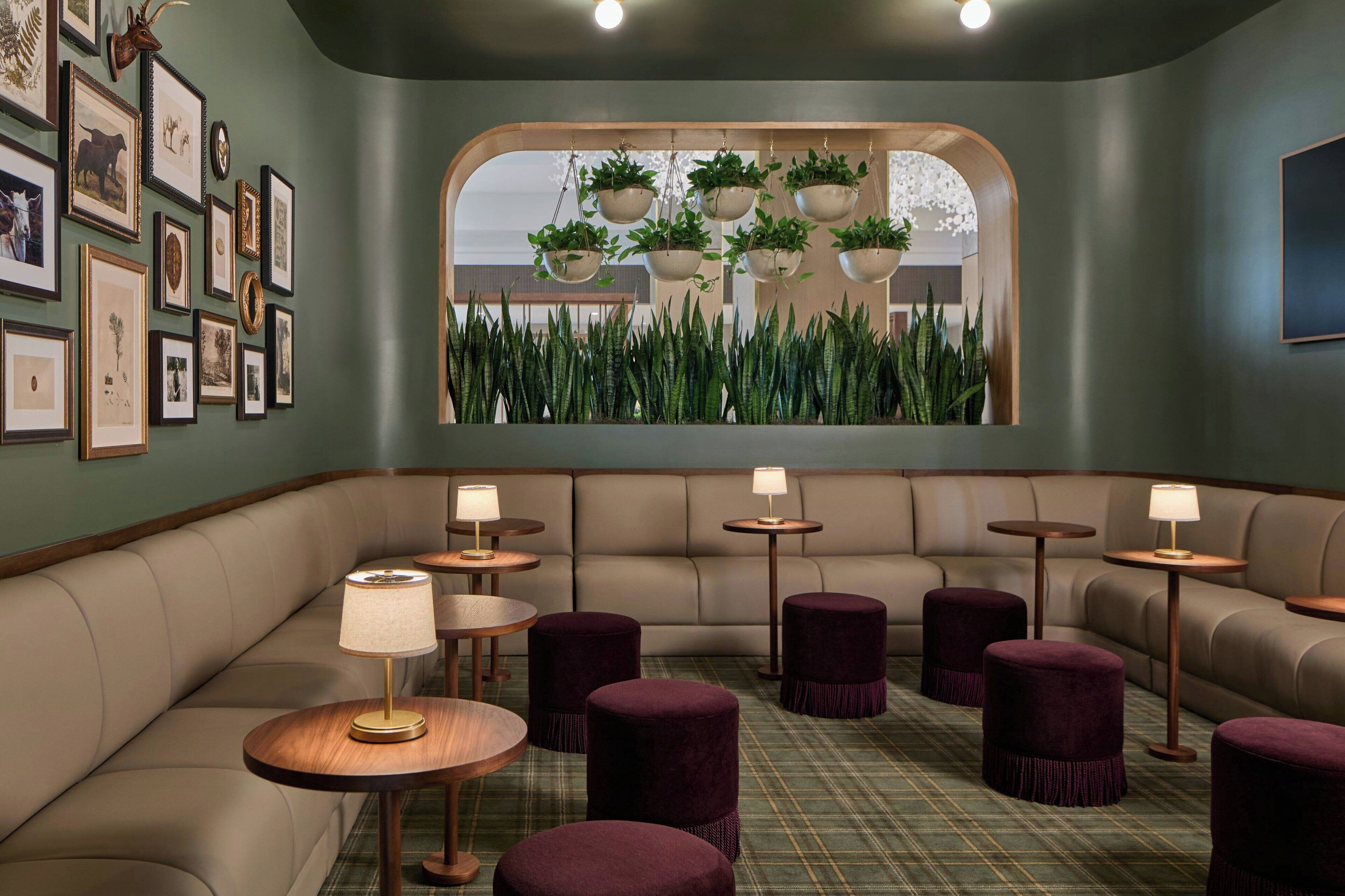 A cozy lounge area with a sofa, round tables, and purple ottomans.