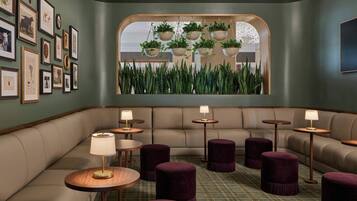A cozy lounge area with a sofa, round tables, and purple ottomans.
