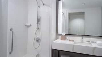 A modern bathroom with a walk-in shower, a bathtub, a large mirror, and a vanity with a sink and towel rack.