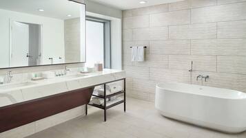 A modern bathroom with a large mirror, a bathtub, and a vanity with a dark wood cabinet.