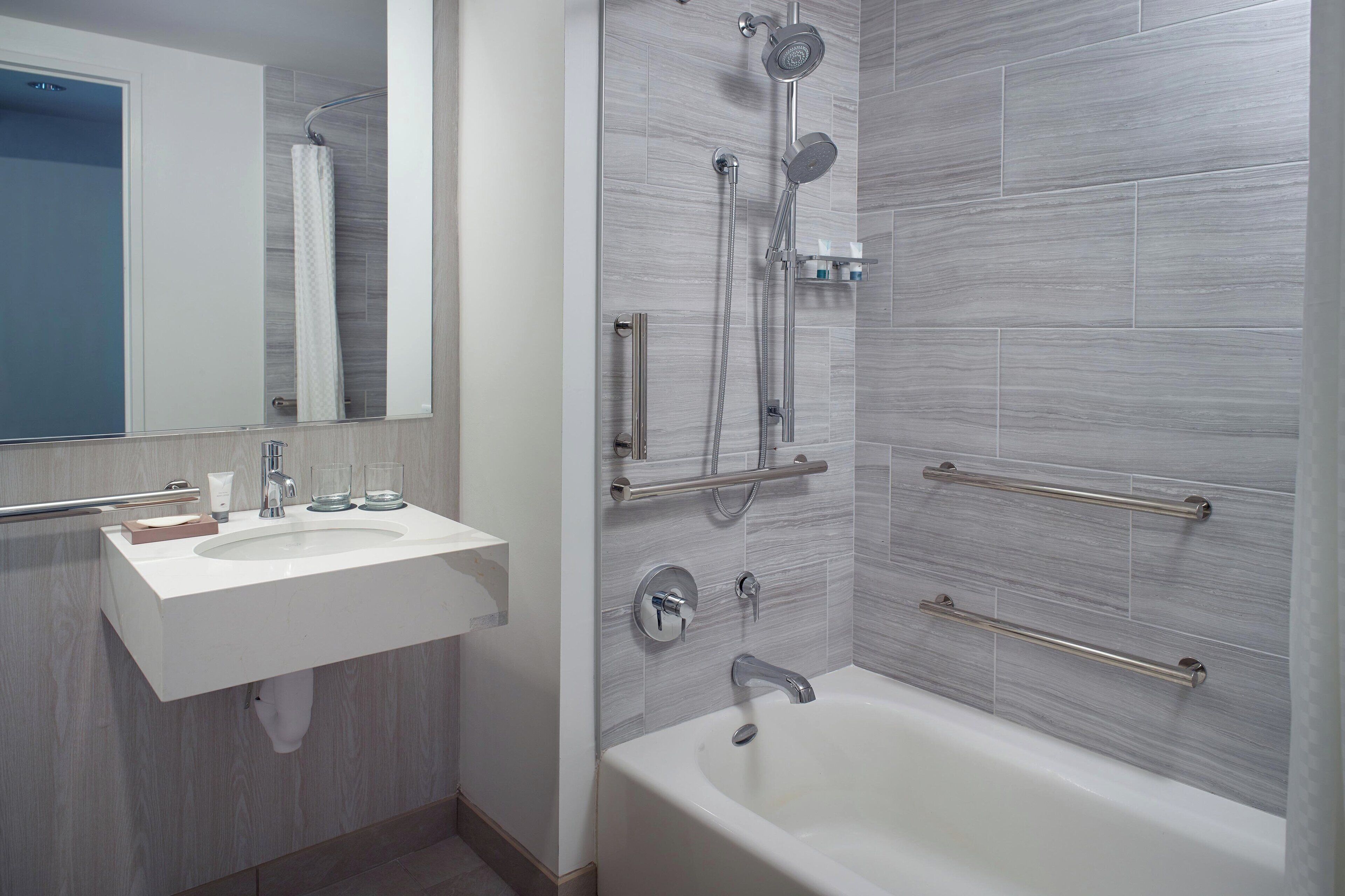 Un baño moderno con un lavabo blanco, una bañera y una ducha con múltiples cabezales.