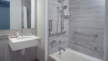 Un baño moderno con un lavabo blanco, una bañera y una ducha con múltiples cabezales.