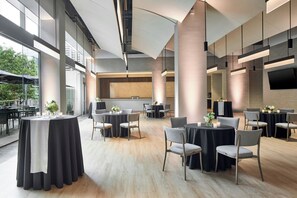 A modern hotel lobby with round tables, chairs, and a large TV screen on the wall. - The Westin Charlotte (Charlotte)
