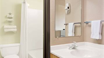 A bathroom with a toilet, a shower, a sink, and a mirror.