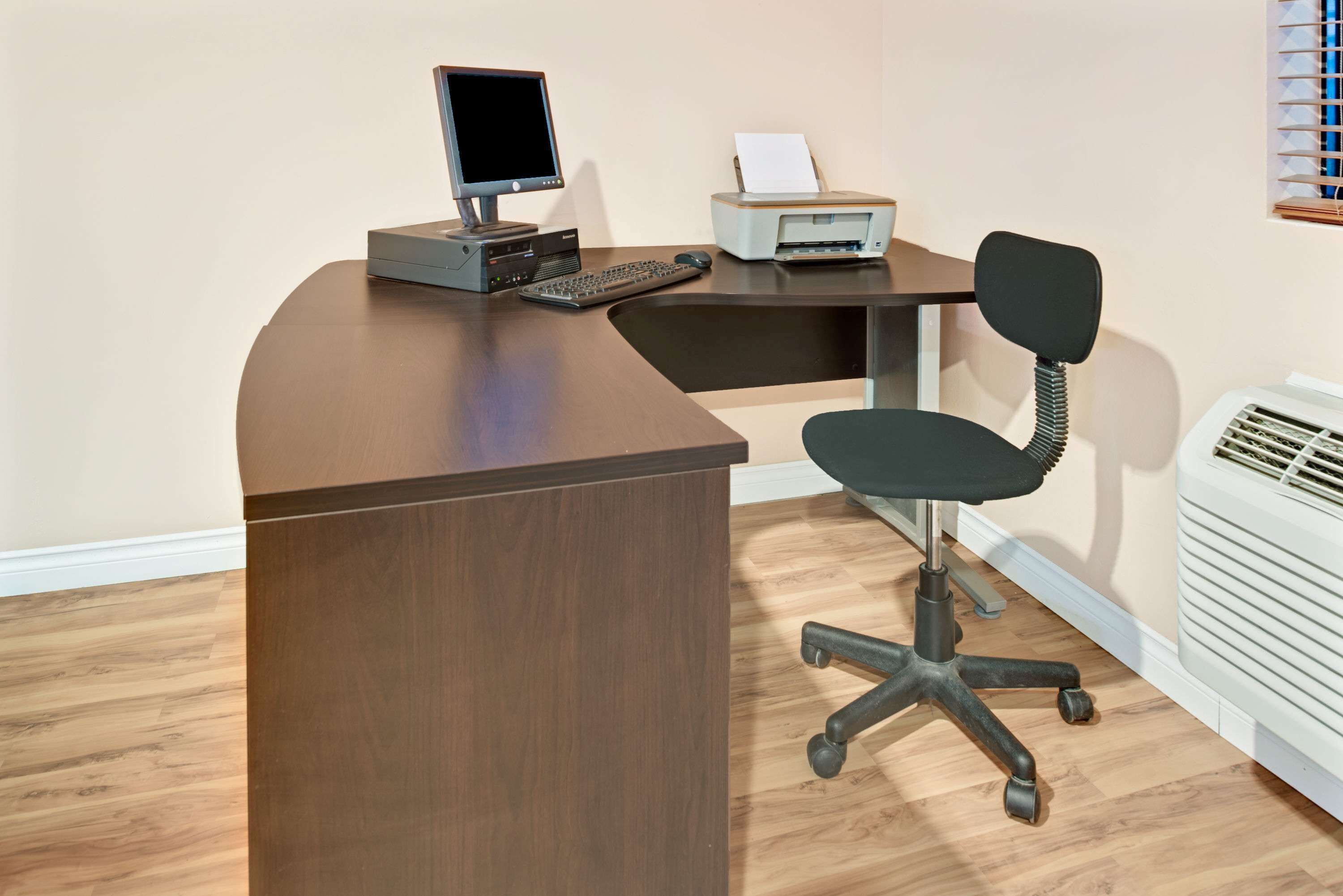 A modern office desk with a computer, keyboard, and printer.