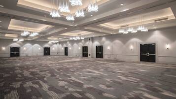 A large, well-lit conference room with multiple doors, a patterned carpet, and modern chandeliers.